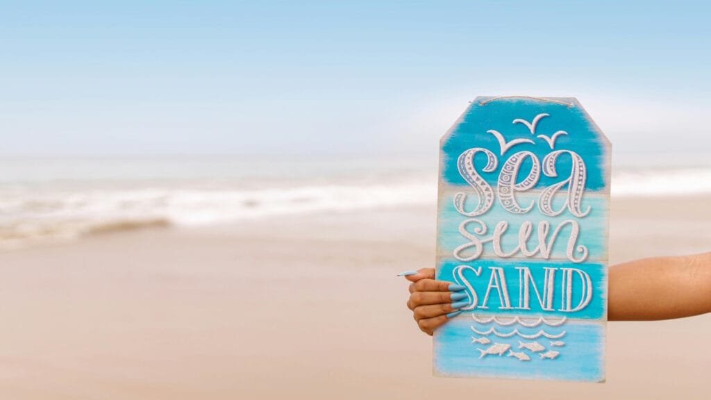 a person holding an advertise sign at the beach