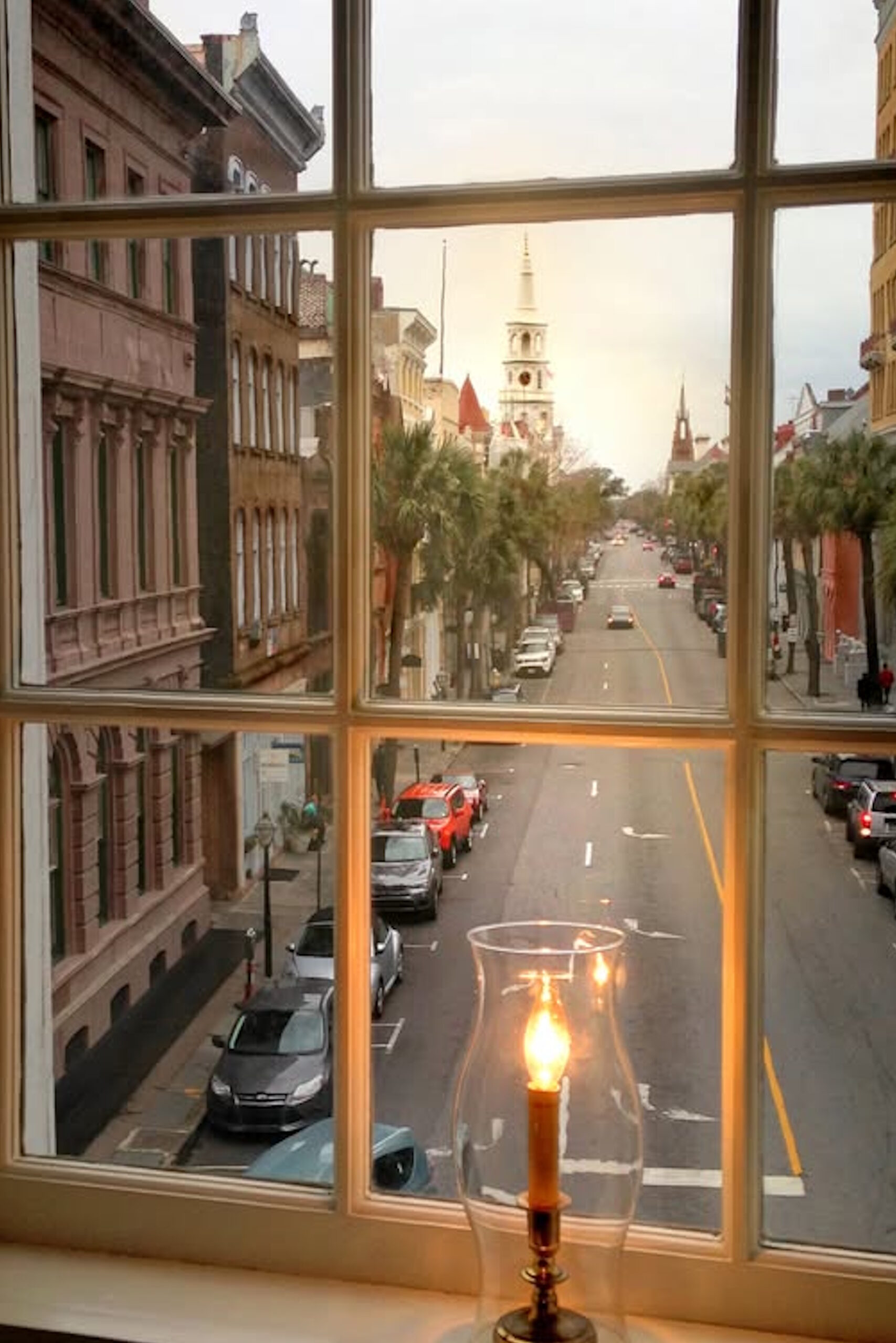 a view of broad street in charleston sc with a candle flickering in the window