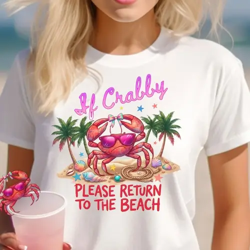 A blonde woman on a sunny beach wearing a white t-shirt featuring a colorful graphic of a grumpy red crab wearing pink sunglasses, surrounded by palm trees and seashells with the quote "If Crabby Please Return to the Beach."