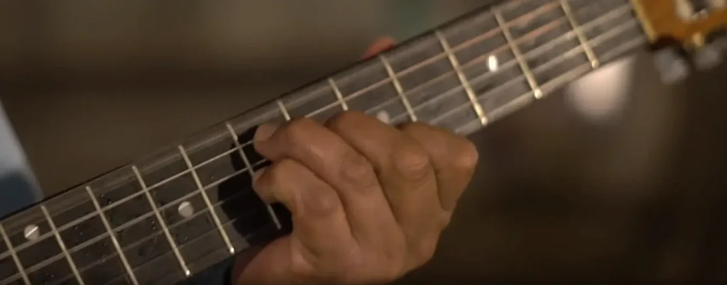 Close-up of a hand playing chords on a guitar, highlighting the warm, musical vibe of a beach day.