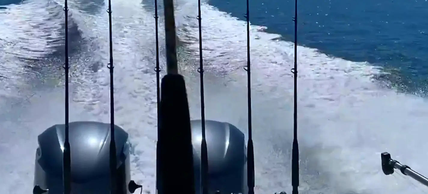 the back of a fishing boat with dual engines and fishing rods