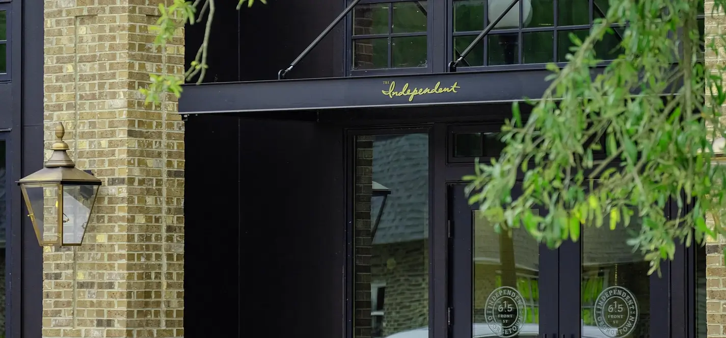 Entrance to The Independent restaurant with brick facade, black awning, and gold lettering at 615 Front Street