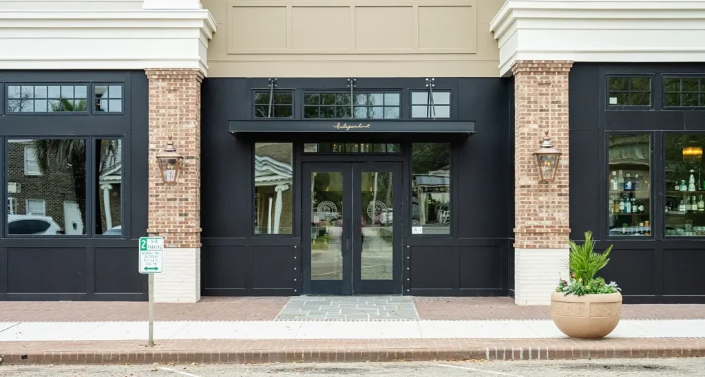 Entrance to The Independent restaurant with brick facade, black awning, and gold lettering at 615 Front Street