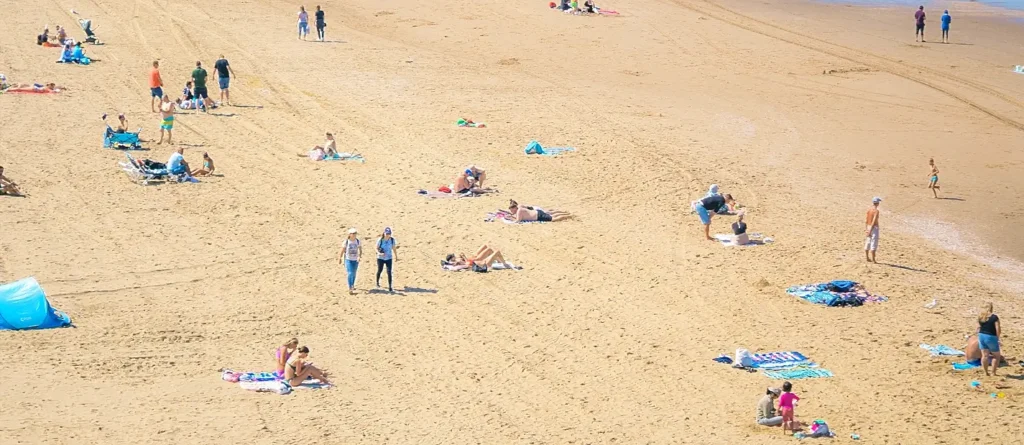 Aerial view of sparse beach crowd relaxing on sand in summer