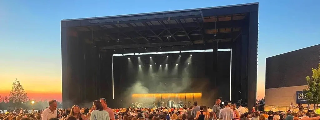 Dramatic sunset view of a concert at Live Oak Bank Pavilion, with the stage lit up and a large crowd gathered under colorful evening skies.