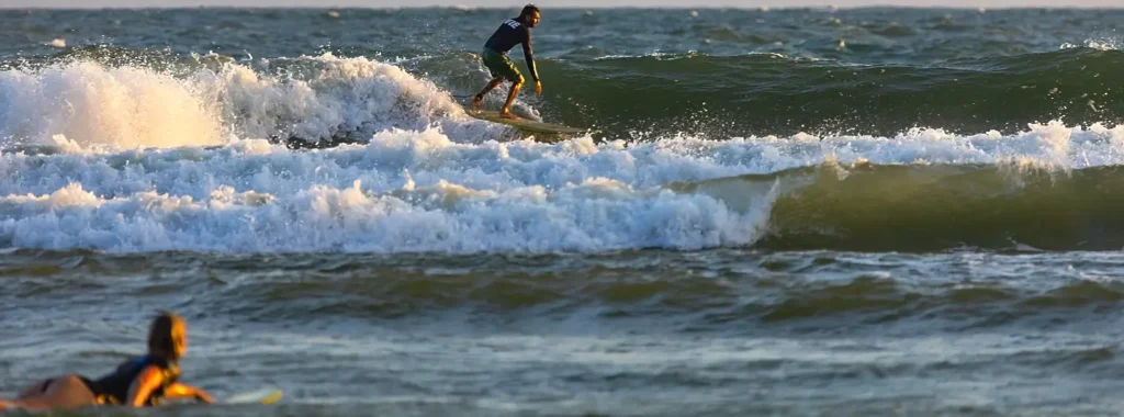 Surfer riding a wave at sunset on the Outer Banks