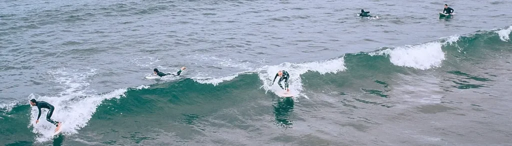 Multiple surfers riding and paddling a wave off the Outer Banks
