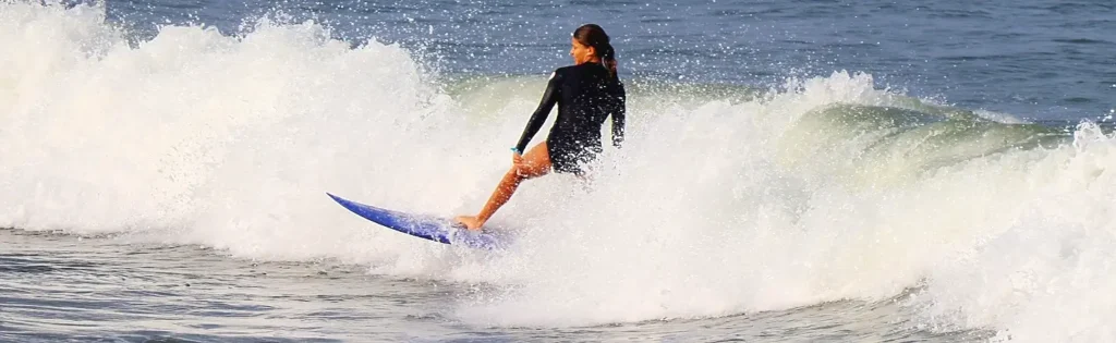 Woman carving a turn on a blue surfboard in the whitewash