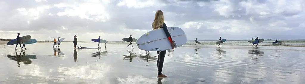 Group of surfers walking along the beach with their boards at low tide