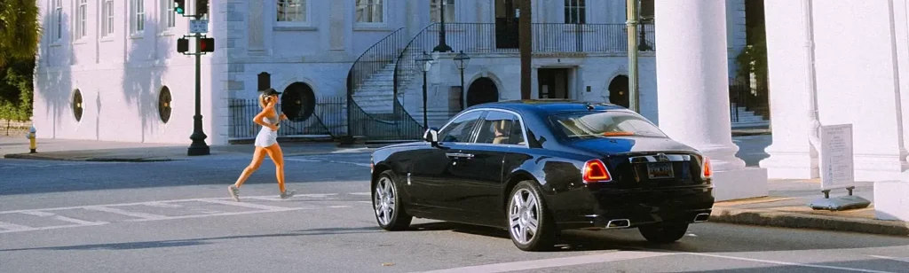 Woman jogging past a black luxury car on a historic Charleston street
