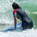 Surfer paddling through breaking whitewater in a wetsuit