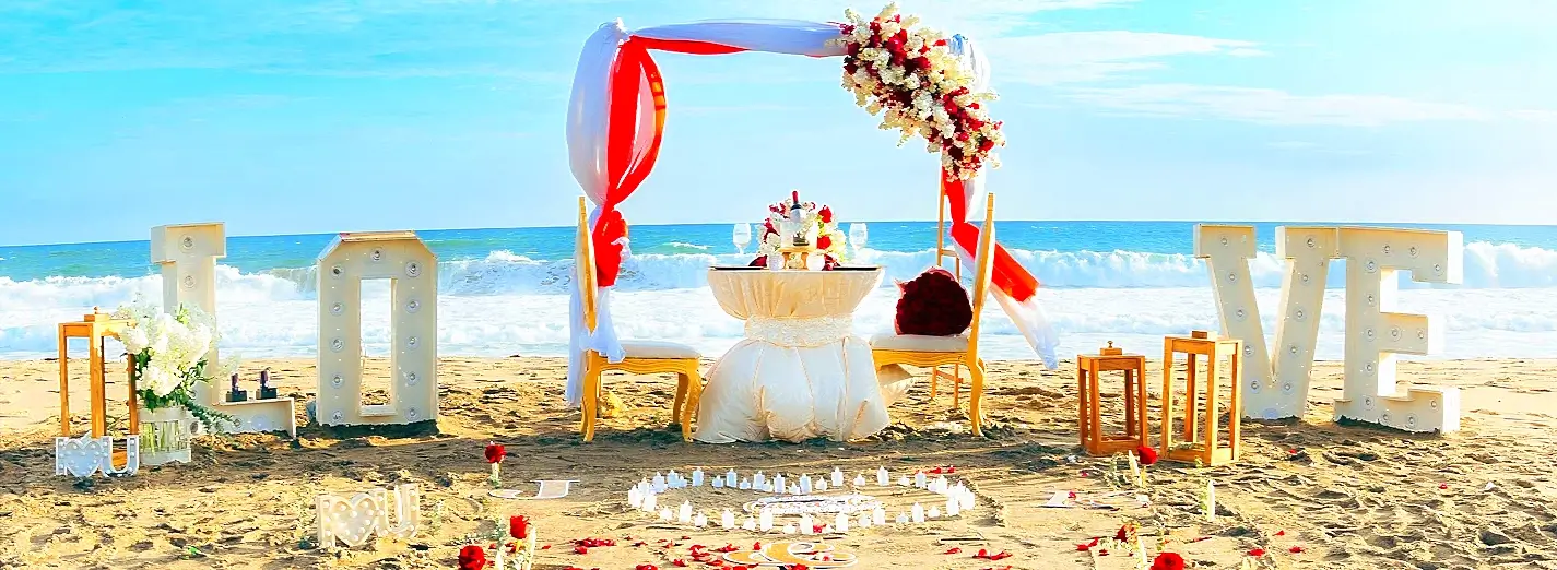 Beach wedding sweetheart table with LOVE letters and floral arch