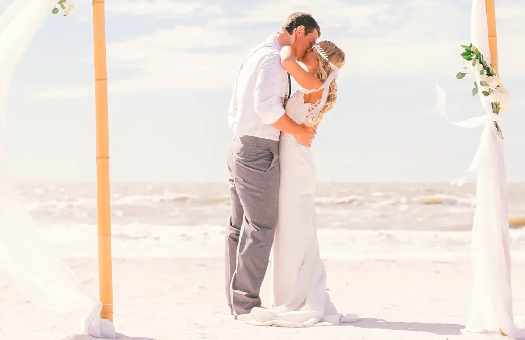 Bride and groom sharing a first kiss at a beach wedding ceremony