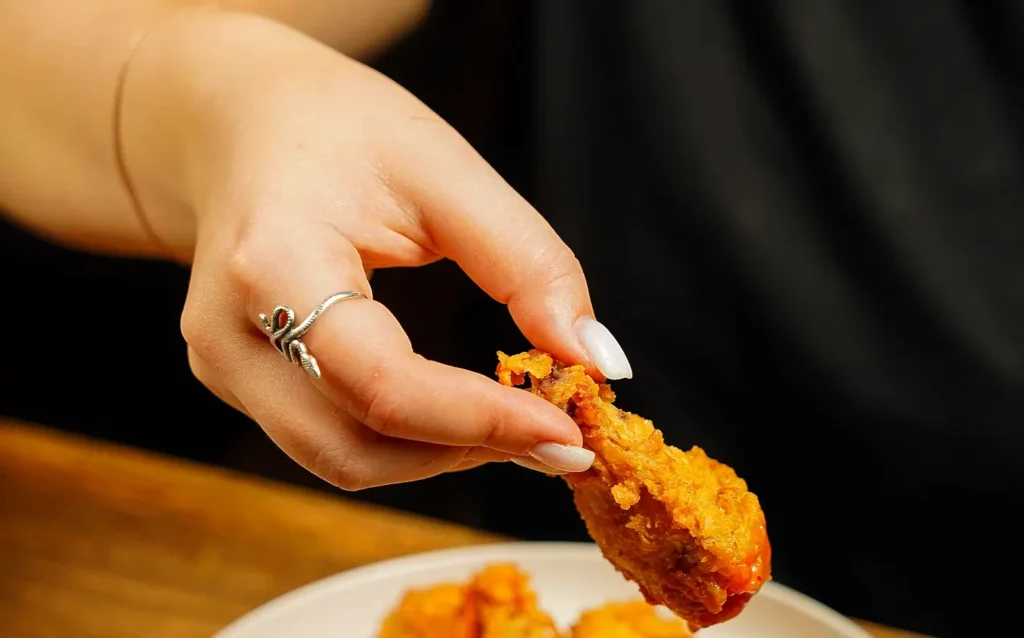 Close-up of a hand picking up a crispy fried chicken wing at an Outer Banks food festival