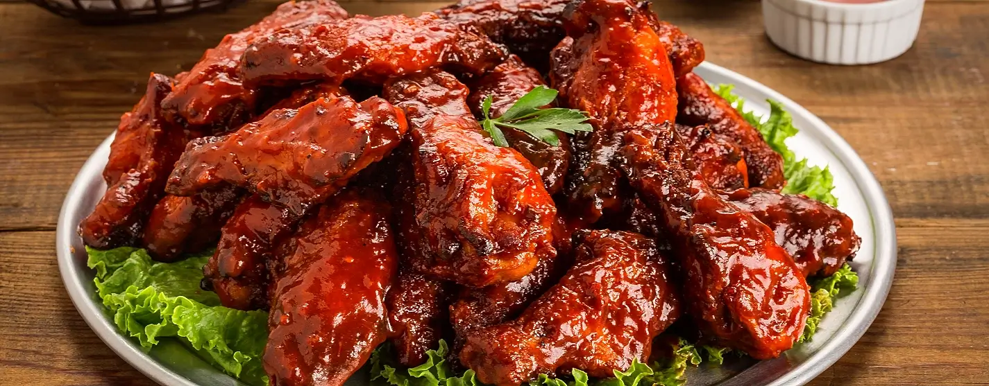 Platter of glazed chicken wings served on lettuce, ready for tasting at Wing Fling Outer Banks