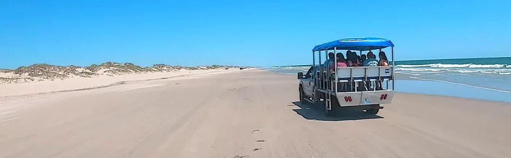 Open-air 4x4 wild horse tour truck carrying visitors along the Corolla beach