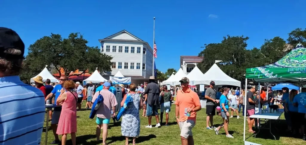 Crowds browsing vendor tents on the lawn at a waterfront Lowcountry festival