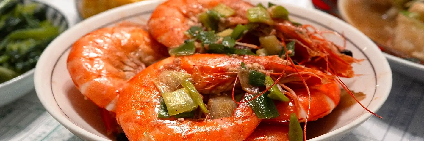 A bowl of whole grilled shrimp garnished with scallions