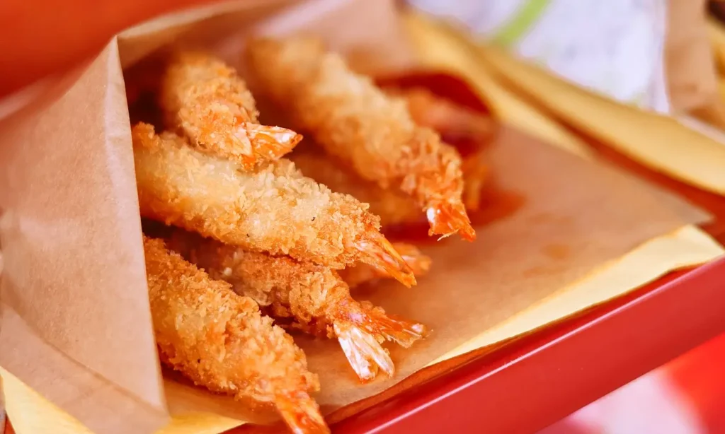 Golden fried coconut shrimp served in a paper takeout tray