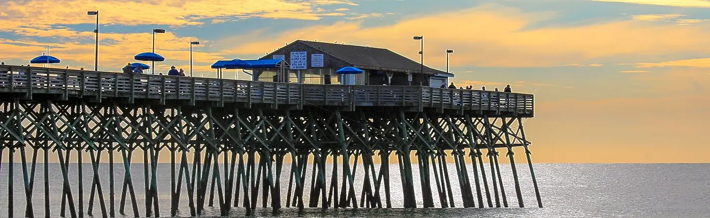 Fishing pier silhouetted against a golden sunset in Garden City, South Carolina