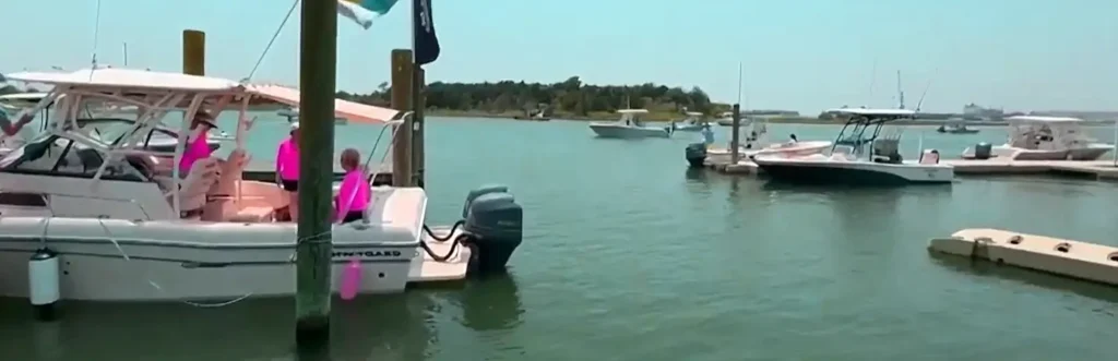 Boat flying pink flags departing the marina with an all-female crew aboard