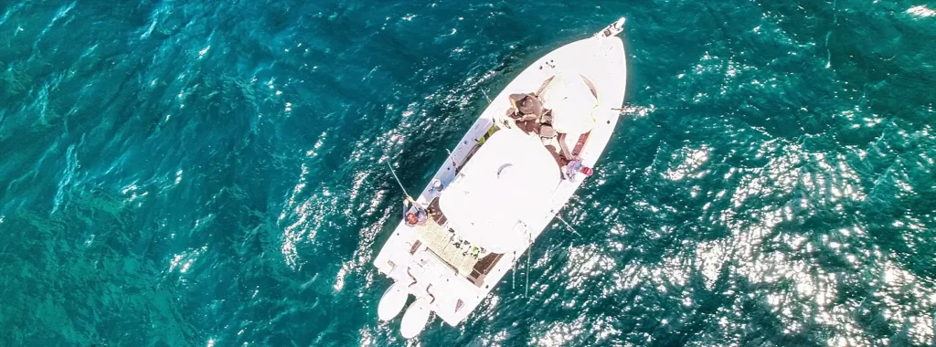 Aerial view of a white sportfishing boat trolling through turquoise water