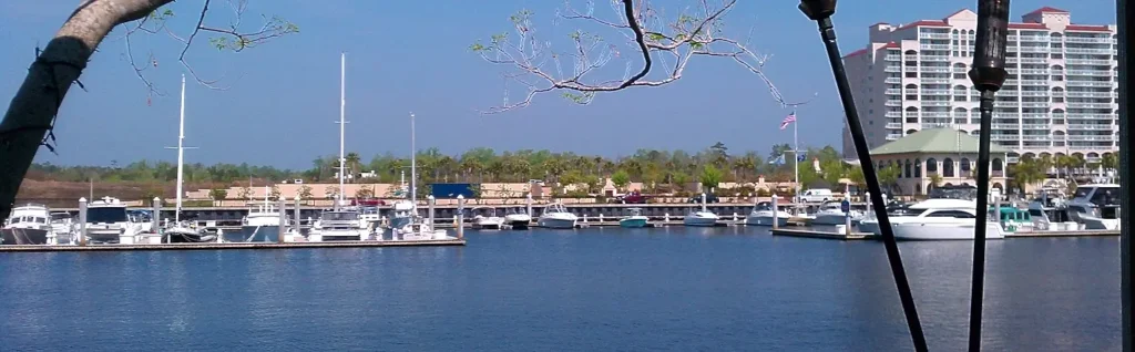 Boats docked at a marina in Myrtle Beach with a waterfront condo tower in the background