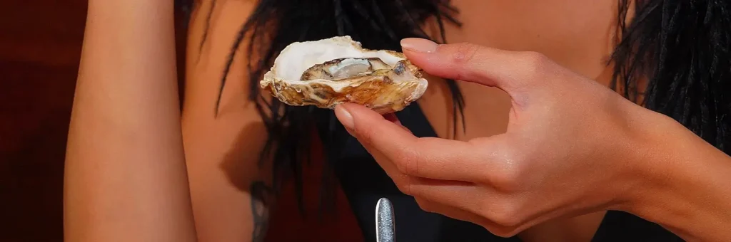 Close-up of a raw oyster on the half shell held near a festival-goer