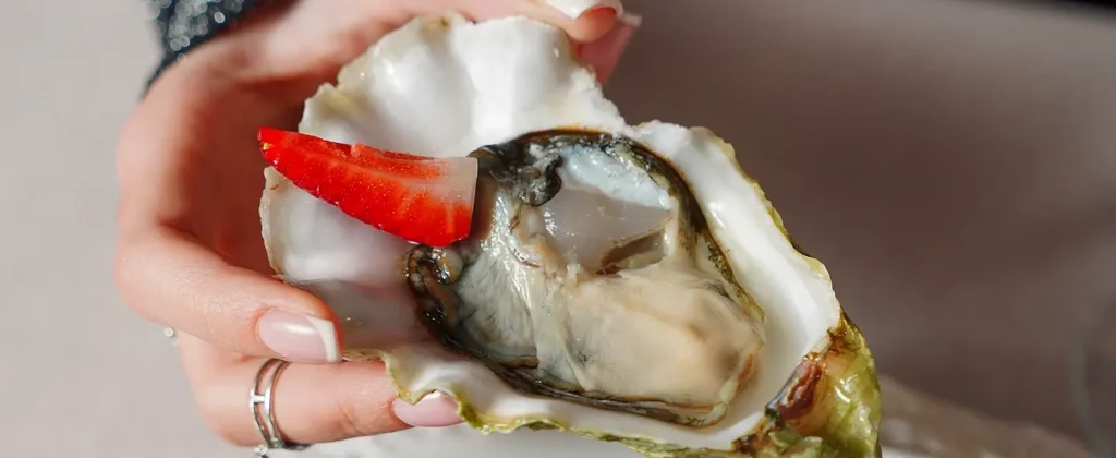 Raw oyster on the half shell garnished with a fresh strawberry slice