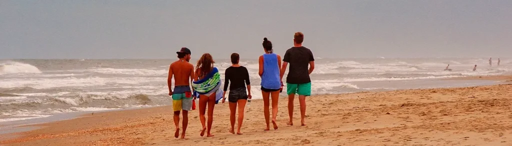 Group of friends walking along the shoreline at an Outer Banks beach