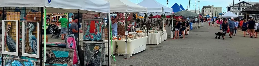 Coastal art vendor tents with pelican and octopus paintings along the festival waterfront