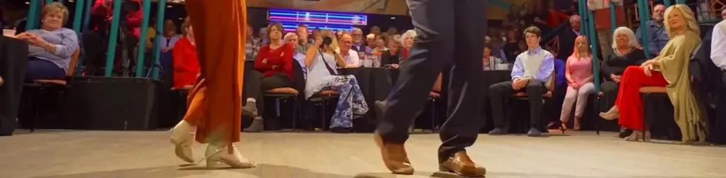 Close-up of shag dancers' footwork on stage with a seated audience watching
