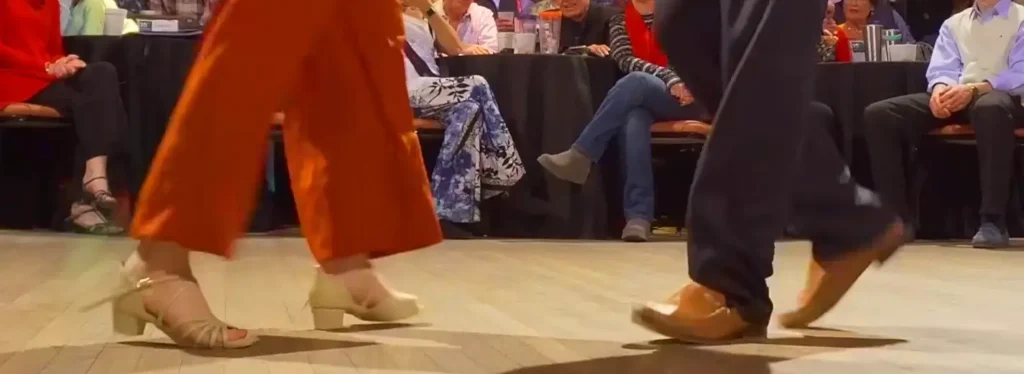 Close-up of a shag couple's footwork mid-step in front of a seated audience
