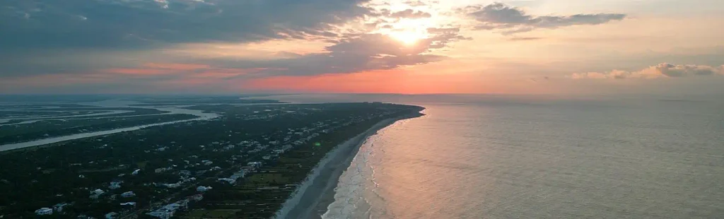 Aerial sunrise view of the Folly Beach coastline curving toward the marsh and Intracoastal Waterway