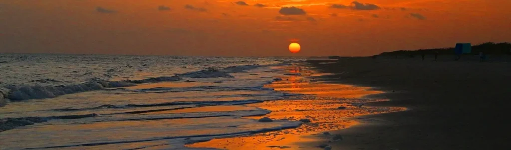 The sun setting over gentle waves on a quiet Carolina coast beach