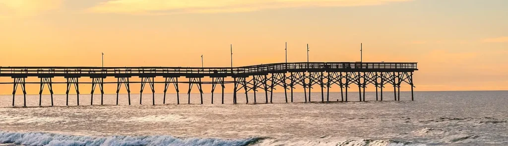 Fishing pier stretching into the ocean at sunset on the Carolina coast