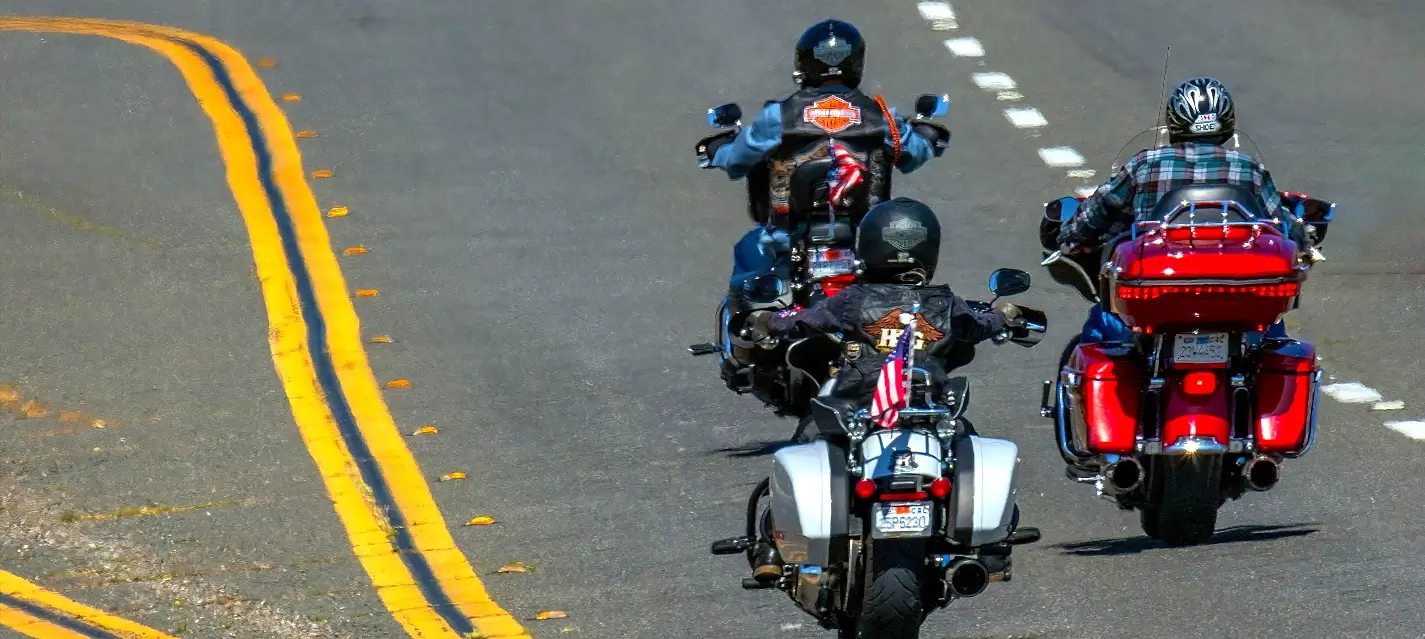 Three motorcycles cruising down a road during Myrtle Beach Bike Week, riders wearing leather jackets and helmets