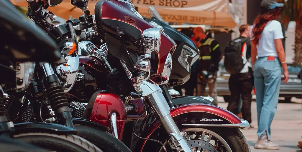 Motorcycles parked outside a crowded vendor area during Myrtle Beach Bike Week with spectators browsing nearby