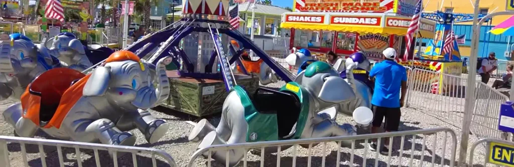 Elephant-themed kiddie ride surrounded by boardwalk food stands at Carolina Beach