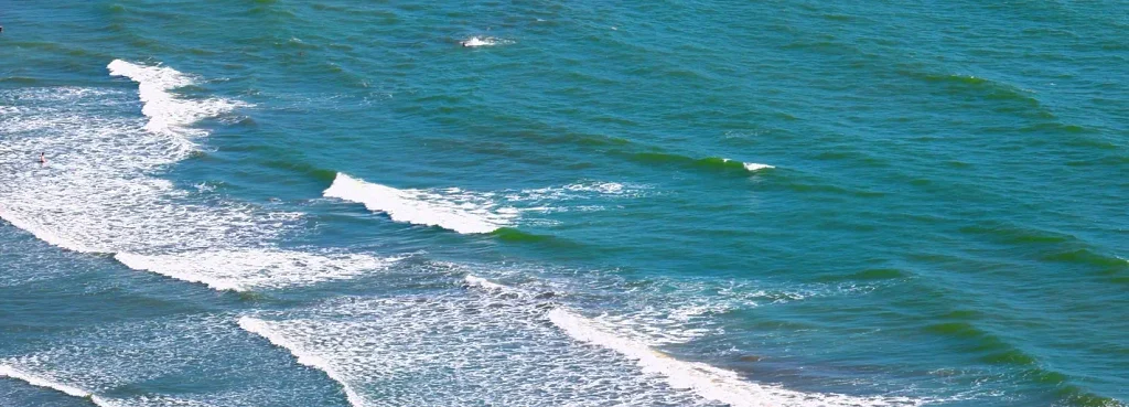 Aerial view of turquoise ocean waves rolling toward the shore