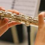 Young musician playing silver flute with sheet music at Lowcountry Jazz Festival