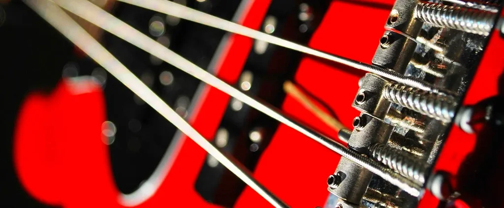 Close-up of electric guitar strings and bridge in red stage lighting at a jazz festival